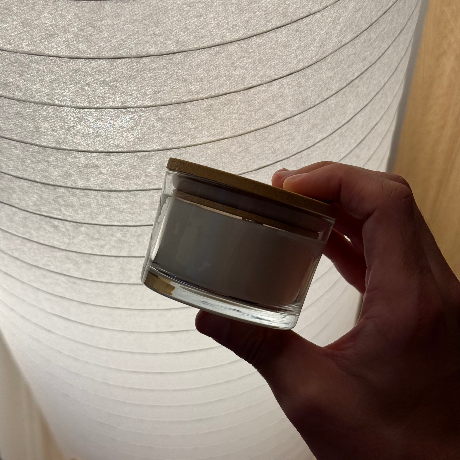 Hand holding a small container in front of a large paper lantern